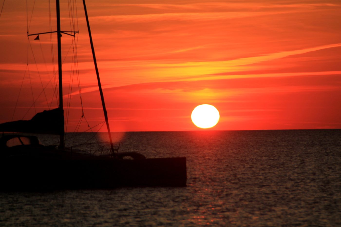 Catamaran en silhouette devant un coucher de soleil rouge sur l&rsquo;océan Indien, à l&rsquo;île Maurice