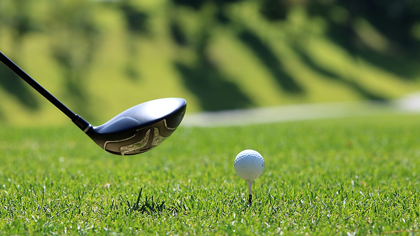 Balle posée sur son tee devant la tête d&rsquo;un driver, au départ d&rsquo;un parcours de golf
