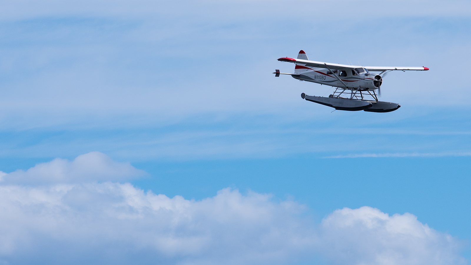 Hydravion à flotteurs en vol au-dessus de l’océan, sous un ciel bleu